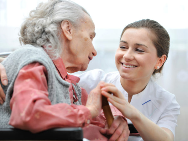 une femme âgée échange avec une assistante médicale qui sourit